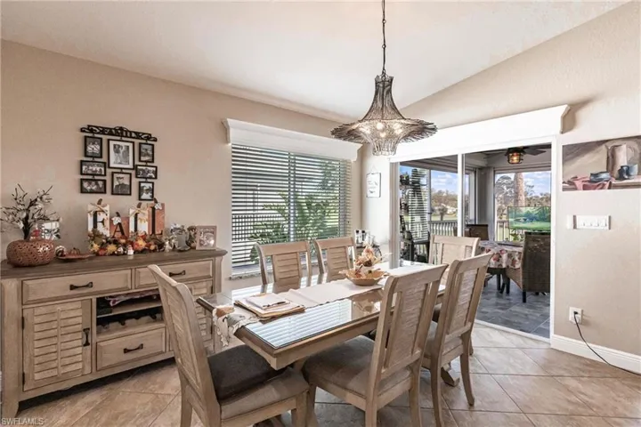 Tiled dining room featuring an inviting chandelier, vaulted ceiling, and plenty of natural light