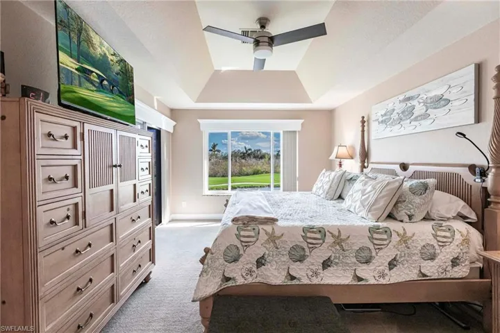 Carpeted bedroom with ceiling fan and a raised ceiling
