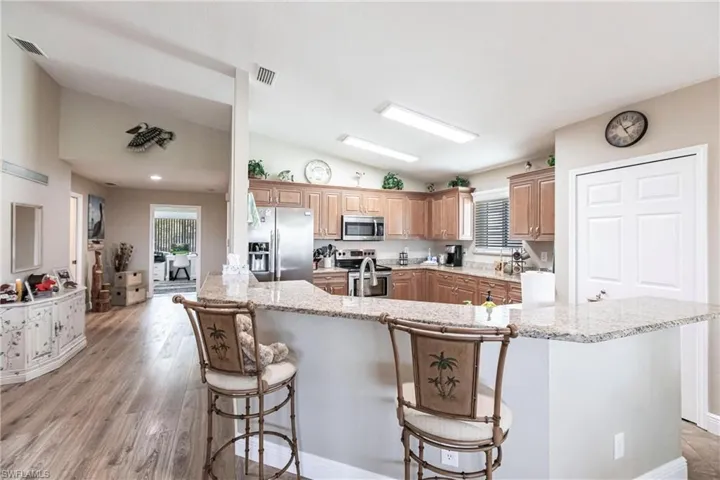 Kitchen with appliances with stainless steel finishes, lofted ceiling, a healthy amount of sunlight, and a kitchen island with sink
