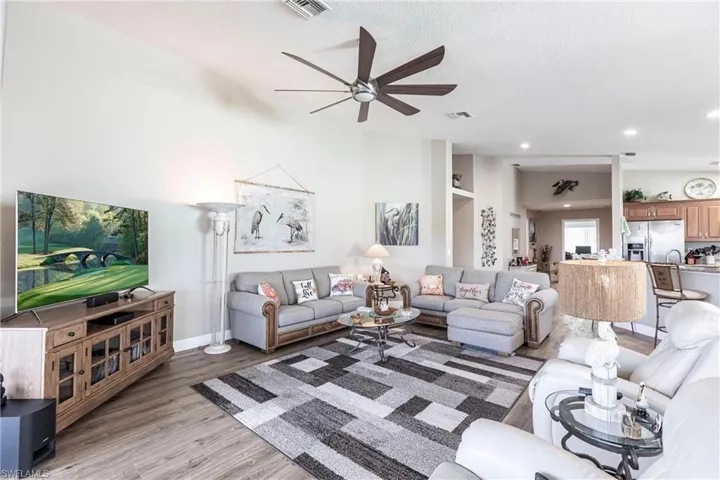 Living room featuring hardwood / wood-style floors, ceiling fan, a textured ceiling, and vaulted ceiling