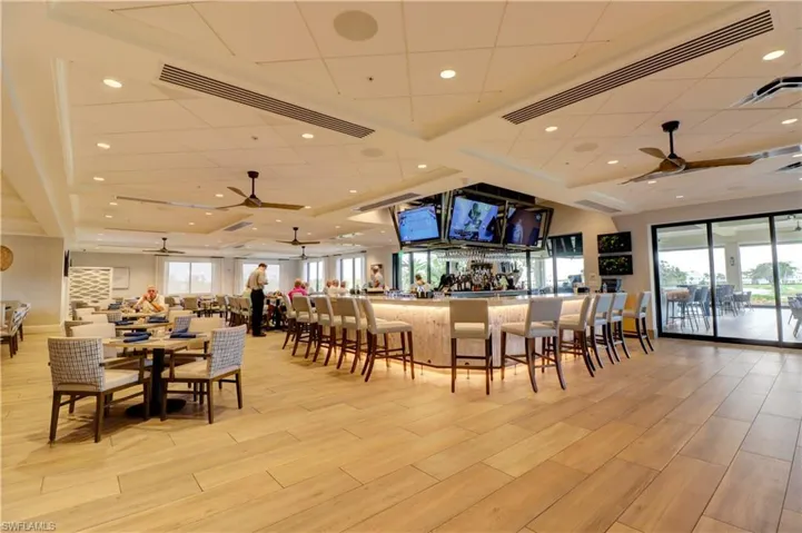 Dining space with light hardwood / wood-style floors, ceiling fan, and indoor bar