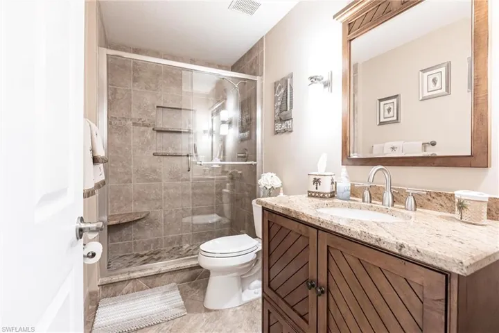 Bathroom with toilet, vanity, tile patterned flooring, and a shower with door