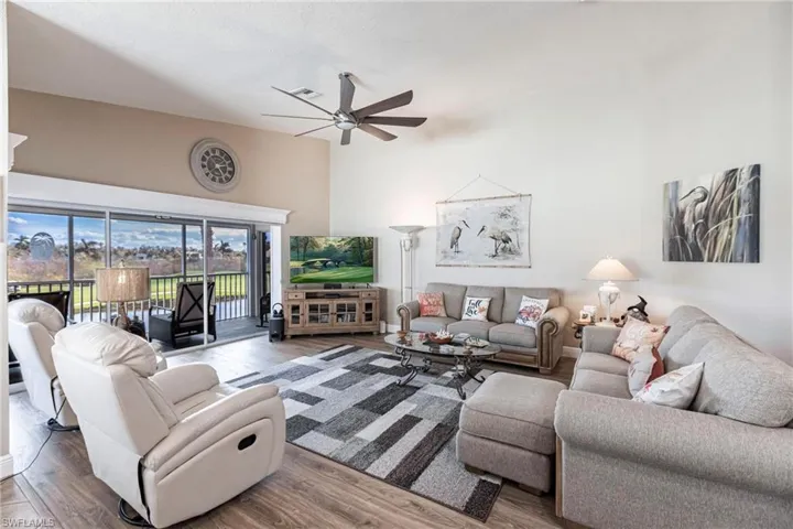 Living room featuring ceiling fan, a high ceiling, and wood-type flooring