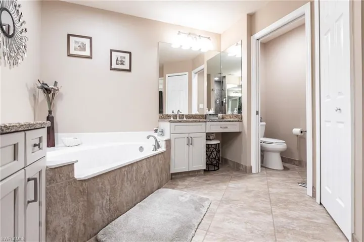 Bathroom with vanity, toilet, and tiled tub