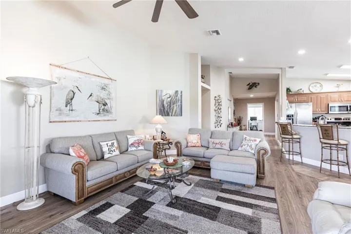 Living room featuring dark hardwood / wood-style flooring, ceiling fan, and vaulted ceiling