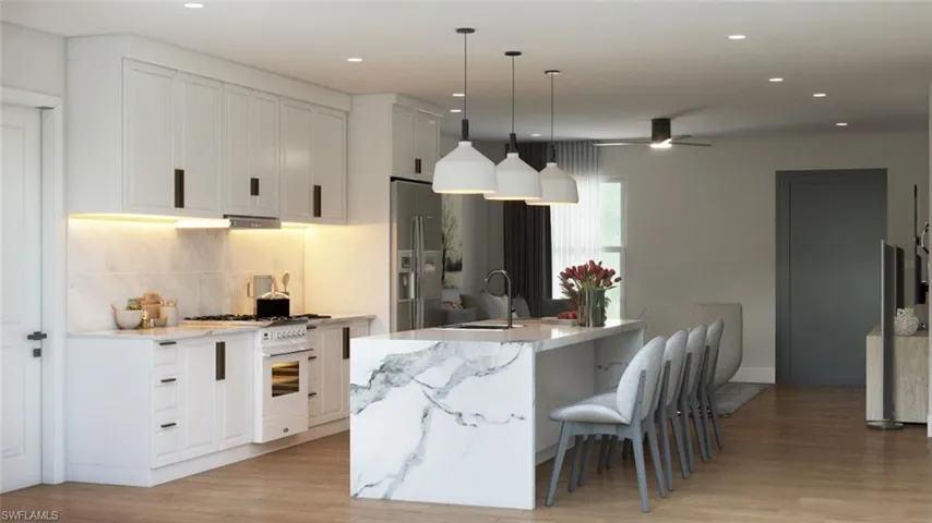 Kitchen with stainless steel refrigerator with ice dispenser, backsplash, an island with sink, light hardwood / wood-style floors, and sink