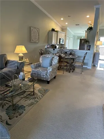 Living room with lofted ceiling, crown molding, a healthy amount of sunlight, and carpet flooring