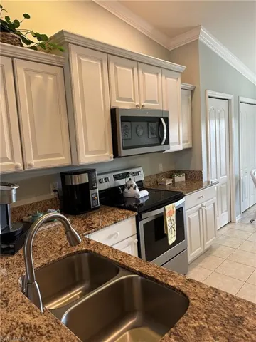 Kitchen featuring lofted ceiling, white cabinets, appliances with stainless steel finishes, and sink
