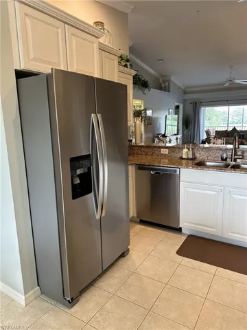 Kitchen with ornamental molding, light tile patterned flooring, stainless steel appliances, and sink