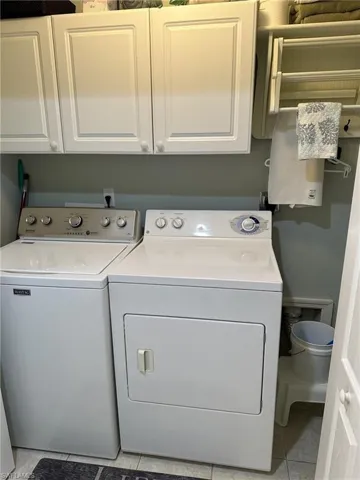 Laundry room featuring light tile patterned flooring, separate washer and dryer, and cabinets