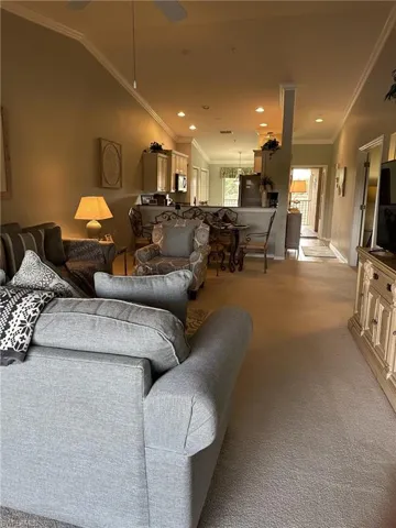 Living room featuring light carpet, crown molding, and vaulted ceiling
