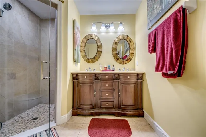 Bathroom featuring double vanity, a shower stall, and light tile patterned floors