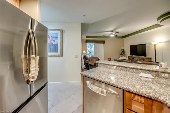 Kitchen with appliances with stainless steel finishes, light stone counters, light tile patterned floors, a ceiling fan, and open floor plan