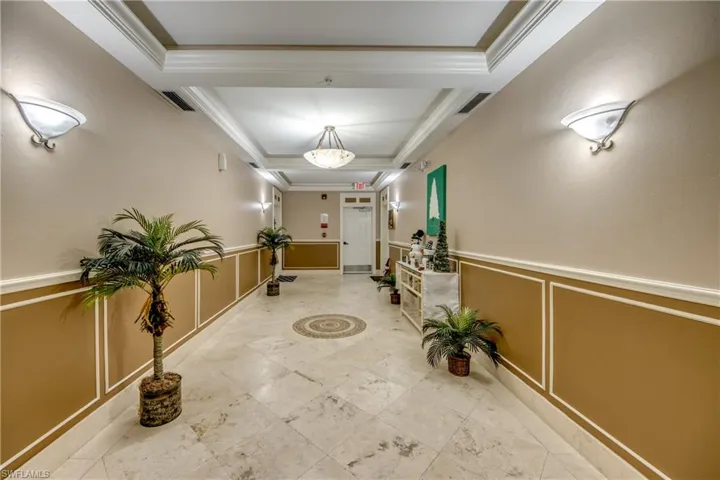 Hall featuring a decorative wall, a wainscoted wall, ornamental molding, and a tray ceiling