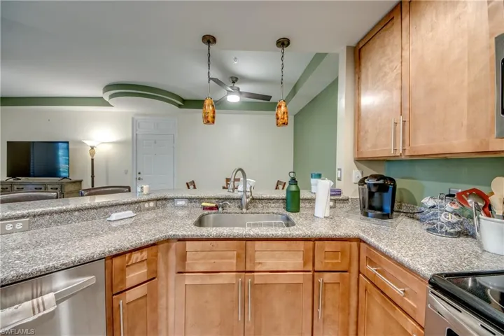 Kitchen featuring dishwasher, hanging light fixtures, light stone counters, and open floor plan