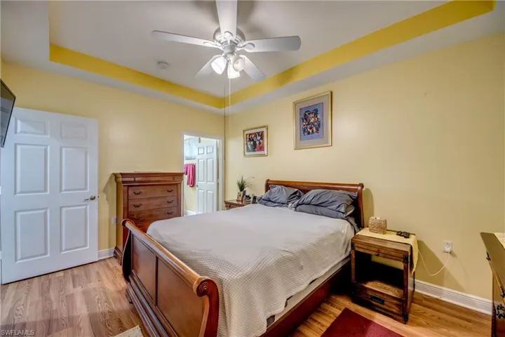 Bedroom featuring a tray ceiling, light wood-style floors, and ceiling fan