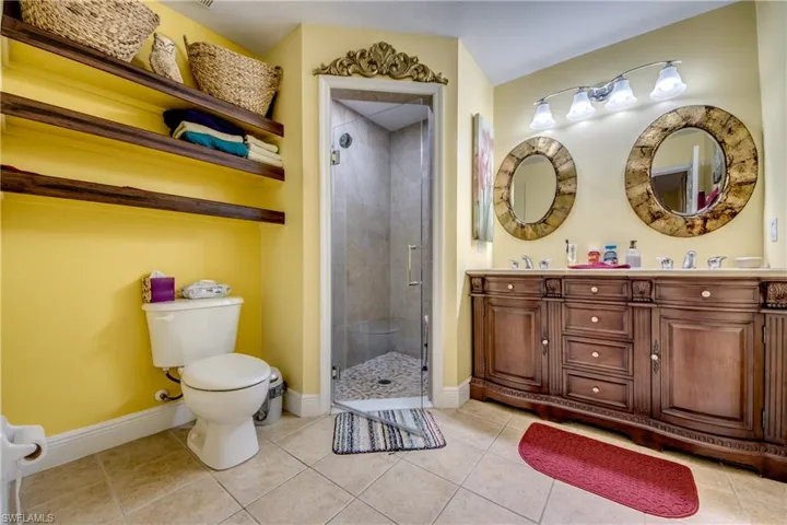 Full bathroom featuring a shower stall, double vanity, and light tile patterned flooring