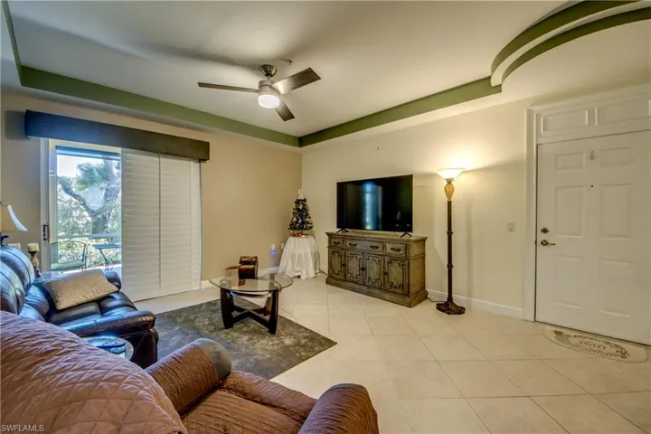 Living area featuring a ceiling fan, light tile patterned floors, and a tray ceiling