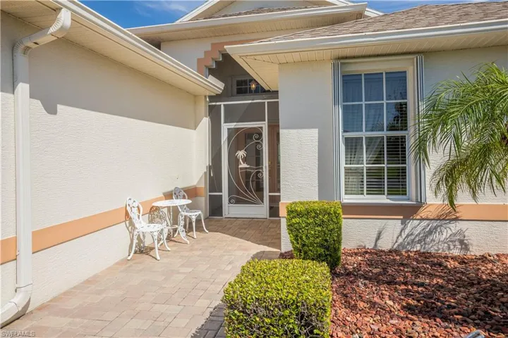 Stucco exterior with decorative banding, multiple windows with blinds, and a screened entry door with a decorative insert