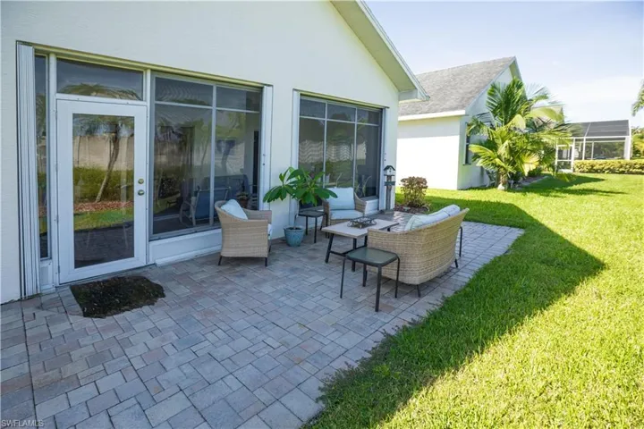 Paver patio with a sliding glass door and screened enclosure, surrounded by a landscaped lawn