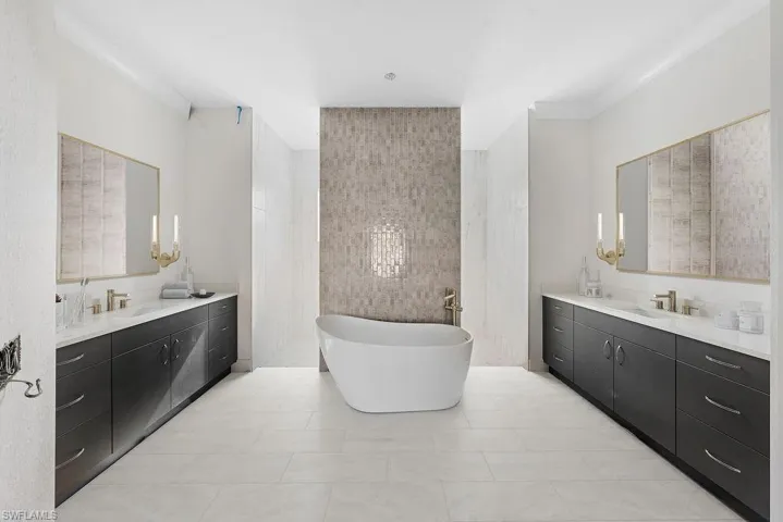 Full bathroom featuring a freestanding tub, two vanities, and light tile patterned flooring