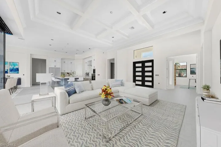 Living area with crown molding, coffered ceiling, beamed ceiling, and a high ceiling