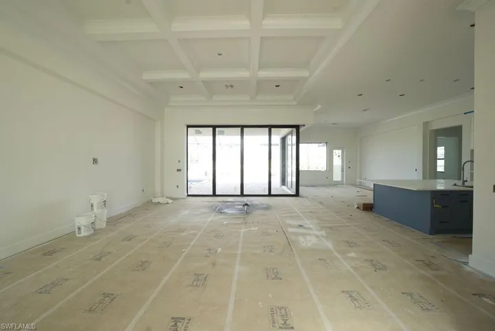 Unfurnished living room with coffered ceiling, beamed ceiling, and crown molding