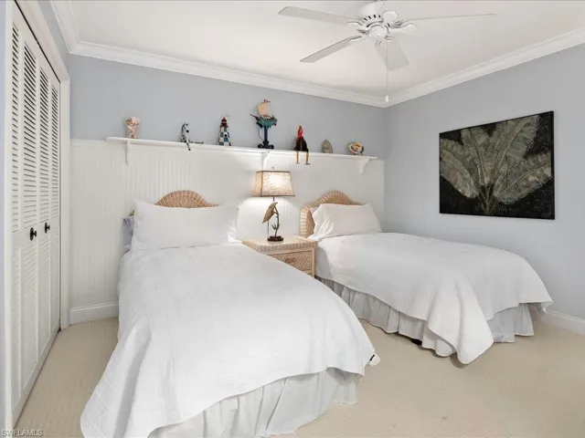 Second bedroom features wall to wall carpet, crown molding, double closets, and ceiling fan.