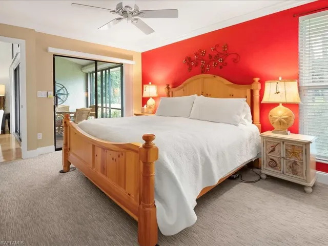 Primary bedroom with sliders to the lanai, wall to wall carpet, crown molding, and ceiling fan.