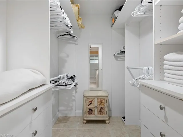 Spacious walk-in closet is to the left of the primary bath and features custom cabinets and a tile patterned floor.