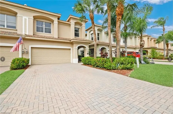 Stucco exterior with arched entryways, a two-car garage, and a paver driveway
