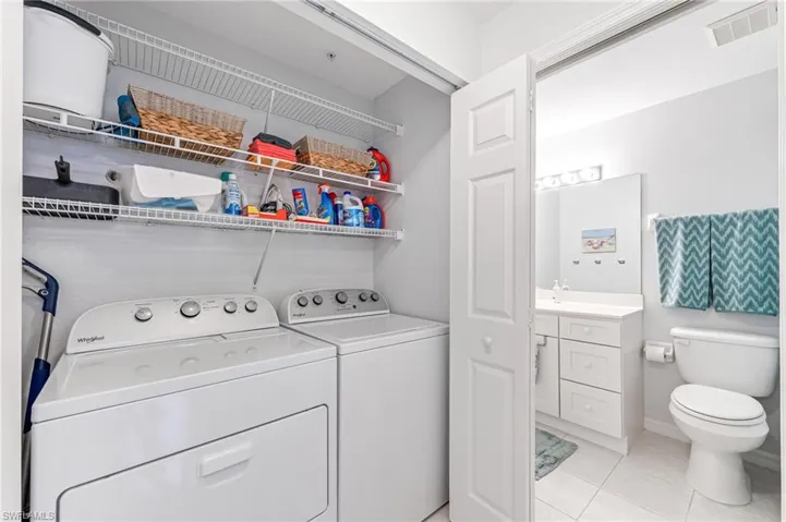 Laundry area featuring washer and dryer, light tile patterned flooring, laundry area, and visible vents