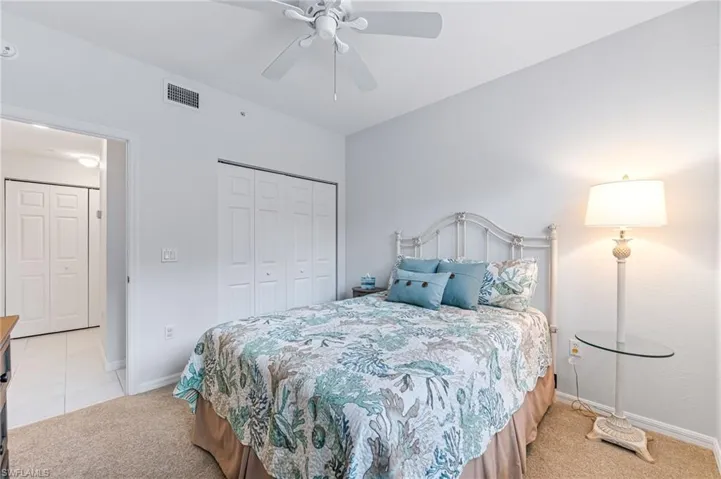 Bedroom with visible vents, a closet, baseboards, light colored carpet, and a ceiling fan