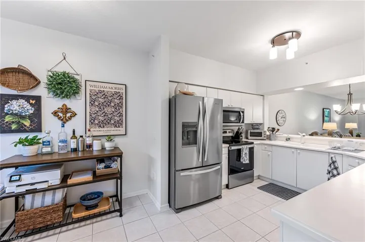 Kitchen with light countertops, light tile patterned flooring, white cabinets, and appliances with stainless steel finishes
