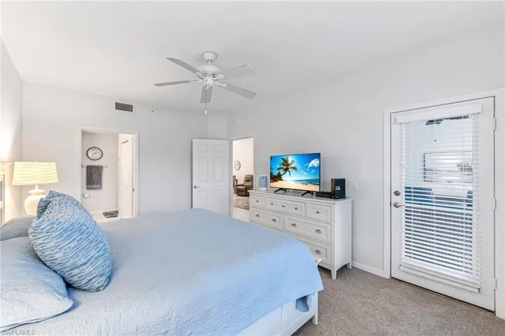 Bedroom with visible vents, baseboards, ensuite bathroom, ceiling fan, and light colored carpet