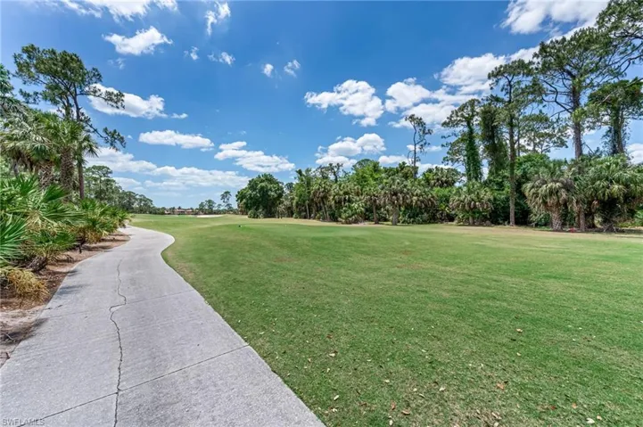 View of home's community with golf course view and a yard