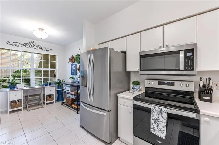 Kitchen featuring light countertops, appliances with stainless steel finishes, light tile patterned floors, and white cabinetry