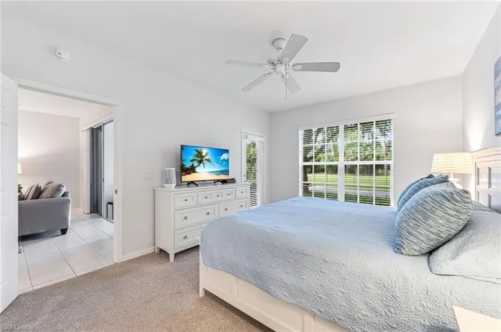 Bedroom with light tile patterned floors, baseboards, ceiling fan, and light carpet