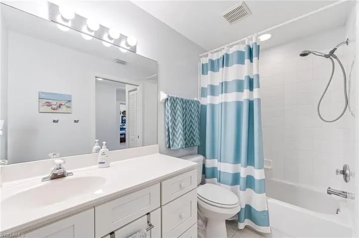 Full bathroom featuring tile patterned flooring, shower / bath combo, vanity, toilet, and visible vents