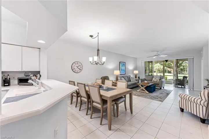 Dining area featuring light tile patterned floors, a toaster, ceiling fan with notable chandelier, and recessed lighting