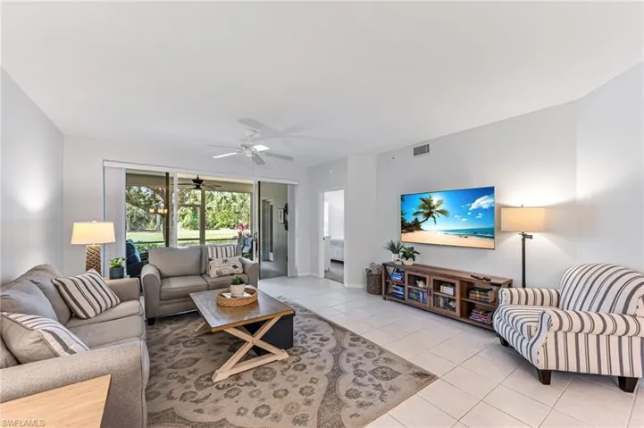 Living area with light tile patterned floors, baseboards, a ceiling fan, and visible vents