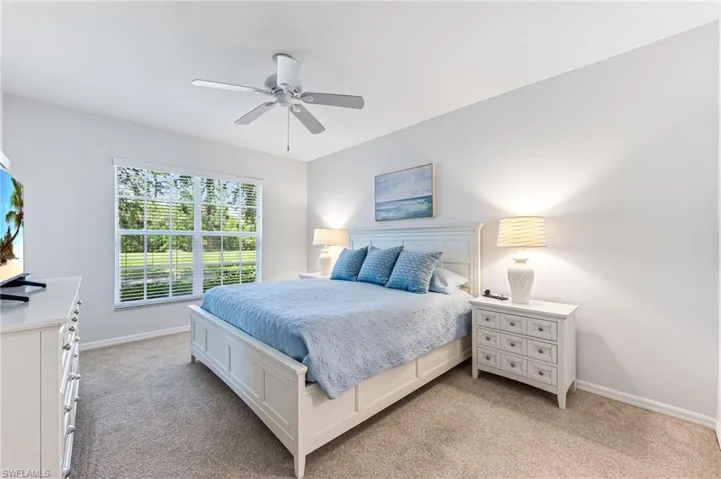 Bedroom with a ceiling fan, baseboards, and light carpet
