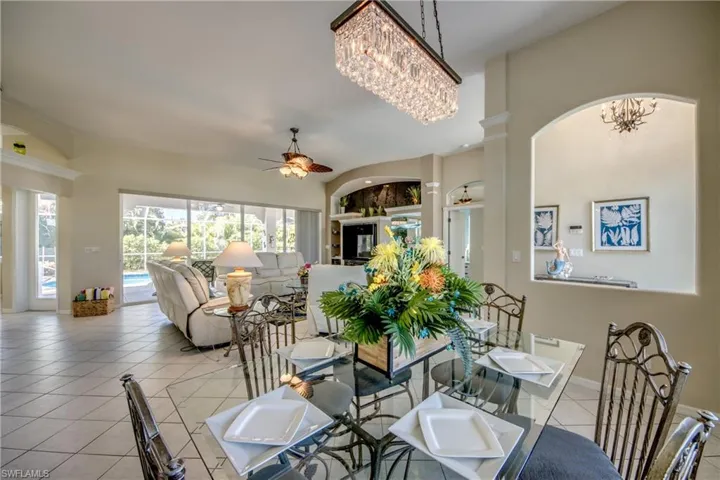 Tiled dining room with built in shelves and ceiling fan with notable chandelier