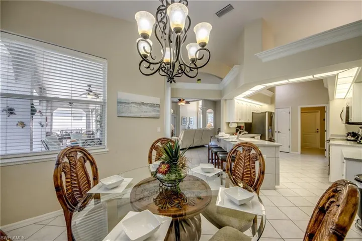 Tiled dining space featuring ceiling fan with notable chandelier