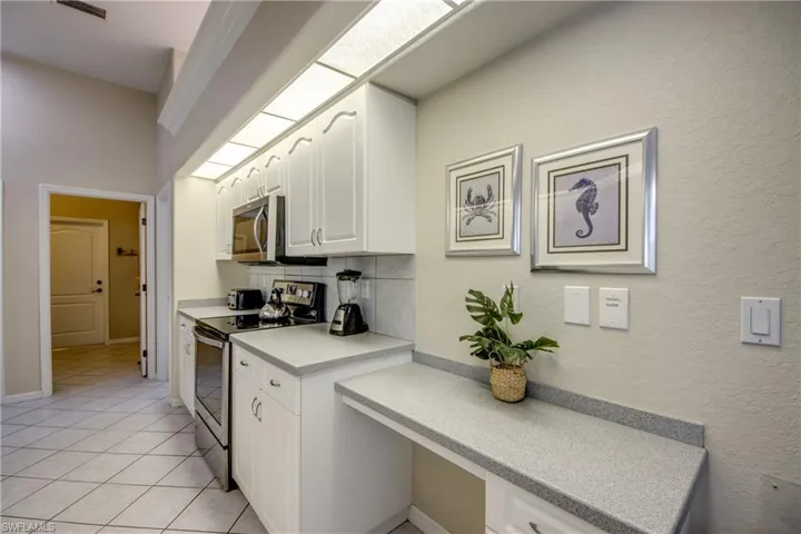 Kitchen featuring electric range oven, white cabinets, backsplash, and light tile floors