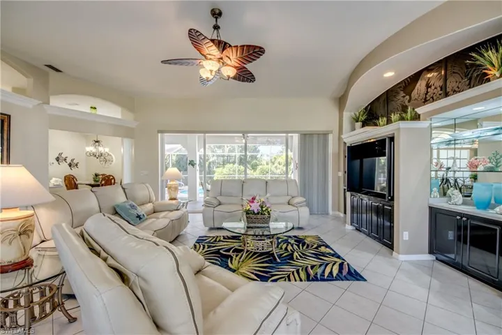 Living room with light tile flooring and ceiling fan with notable chandelier