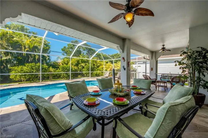 View of pool with a patio, glass enclosure, and ceiling fan