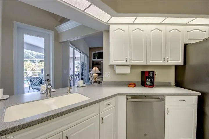 Kitchen featuring white cabinetry, sink, fridge, and stainless steel dishwasher