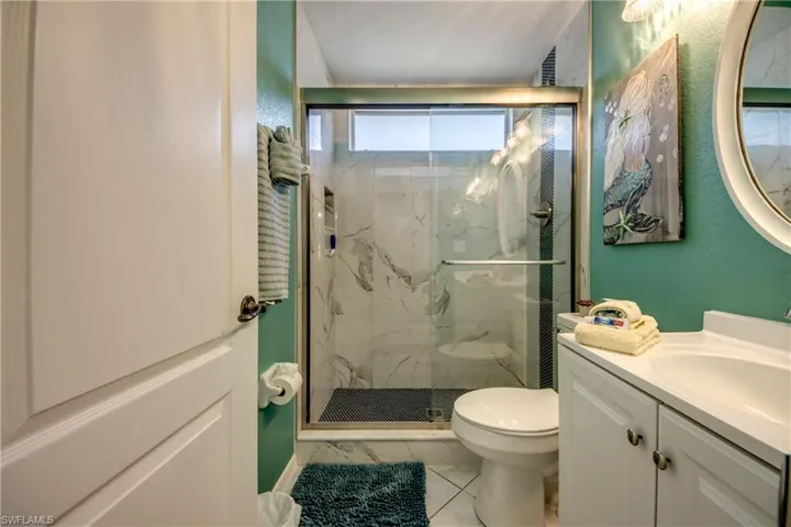 Bathroom with an enclosed shower, vanity, toilet, and tile floors