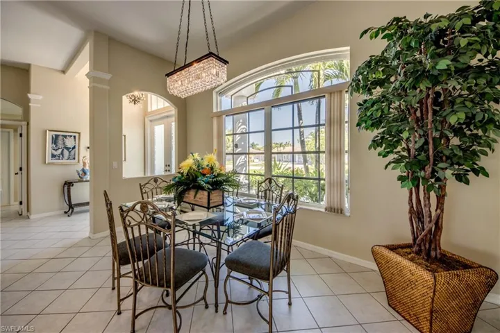 Tiled dining room with a notable chandelier, plenty of natural light, and decorative columns
